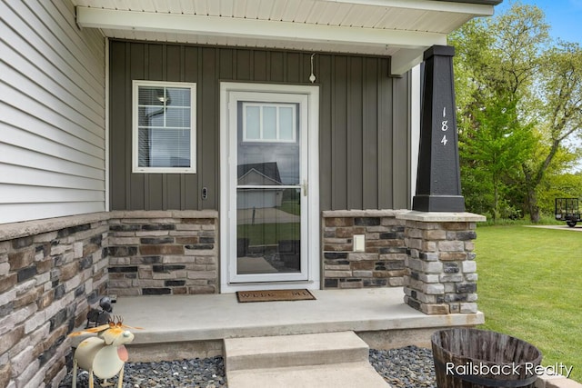 184 Dana Ln, Sand Lake, MI 49343 - doorway to property featuring stone siding, board and batten siding, and a lawn