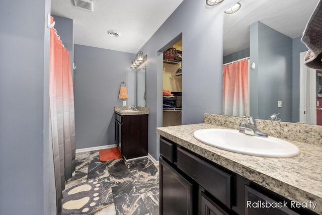 184 Dana Ln, Sand Lake, MI 49343 - bathroom with marble look tiles, vanity, baseboards, a walk in closet, and curtained shower