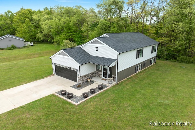 184 Dana Ln, Sand Lake, MI 49343 - back of house featuring a garage, concrete driveway, a lawn, and a shingled roof