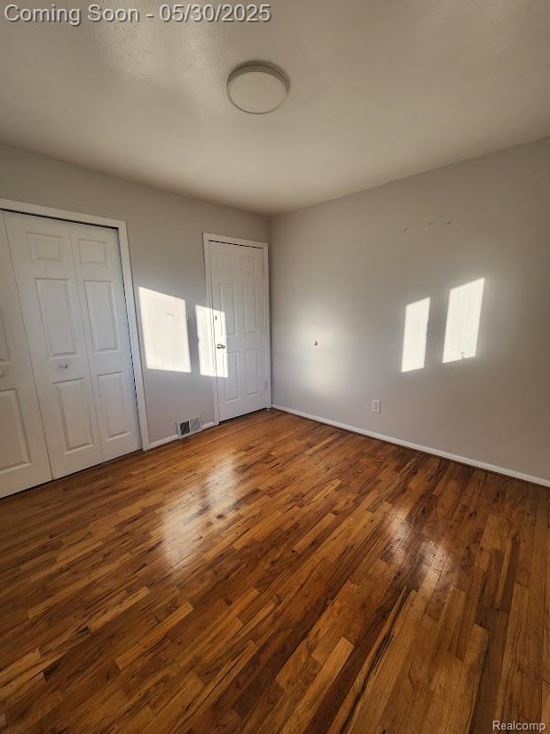 2625 Winston Dr, Sterling Heights, MI 48310 - unfurnished bedroom with two closets, wood-type flooring, and baseboards
