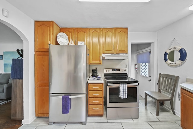 912 Gerald Ave, Jackson, MI 49203 - kitchen with stainless steel appliances, under cabinet range hood, arched walkways, light countertops, and baseboards
