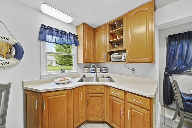 912 Gerald Ave, Jackson, MI 49203 - kitchen featuring a sink, light countertops, open shelves, and brown cabinets