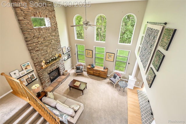 29811 Bradford Dr, New Hudson, MI 48165 - living area with healthy amount of natural light, a stone fireplace, a high ceiling, a ceiling fan, and wood finished floors
