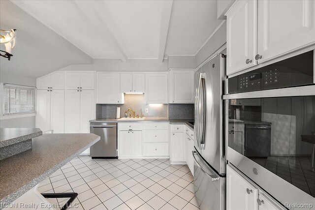 8569 Cooley Beach Dr, White Lake, MI 48386 - kitchen featuring stainless steel appliances, white cabinetry, tasteful backsplash, light tile patterned flooring, and a sink