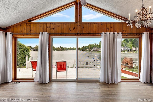 8569 Cooley Beach Dr, White Lake, MI 48386 - doorway with lofted ceiling, a chandelier, wood walls, wood finished floors, and healthy amount of natural light