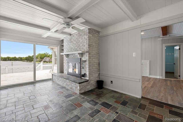 8569 Cooley Beach Dr, White Lake, MI 48386 - unfurnished living room with a brick fireplace, beam ceiling, ceiling fan, and stone tile flooring