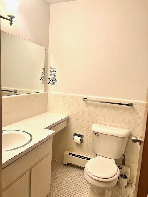 19160 Winston St Unit 206, Detroit, MI 48219 - bathroom featuring a baseboard heating unit, vanity, toilet, tile walls, and tile patterned floors