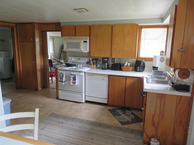 6248 Howard St, Gladwin, MI 48624 - kitchen with white appliances, washer / dryer, light countertops, and brown cabinetry
