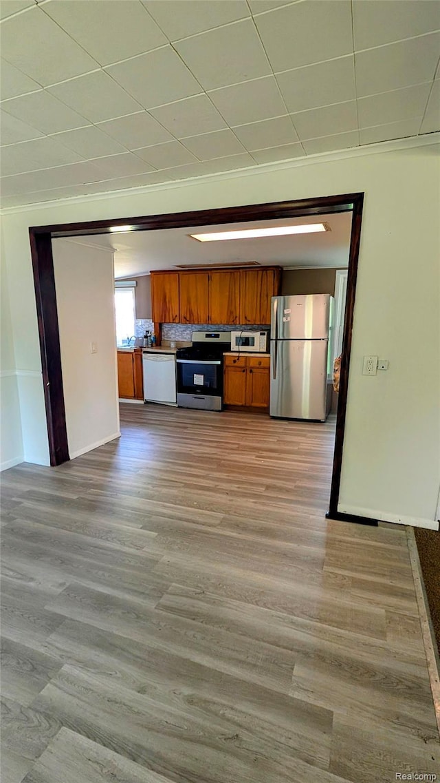 703 Queen St, Owosso, MI 48867 - kitchen featuring appliances with stainless steel finishes, brown cabinets, light wood-style flooring, and baseboards