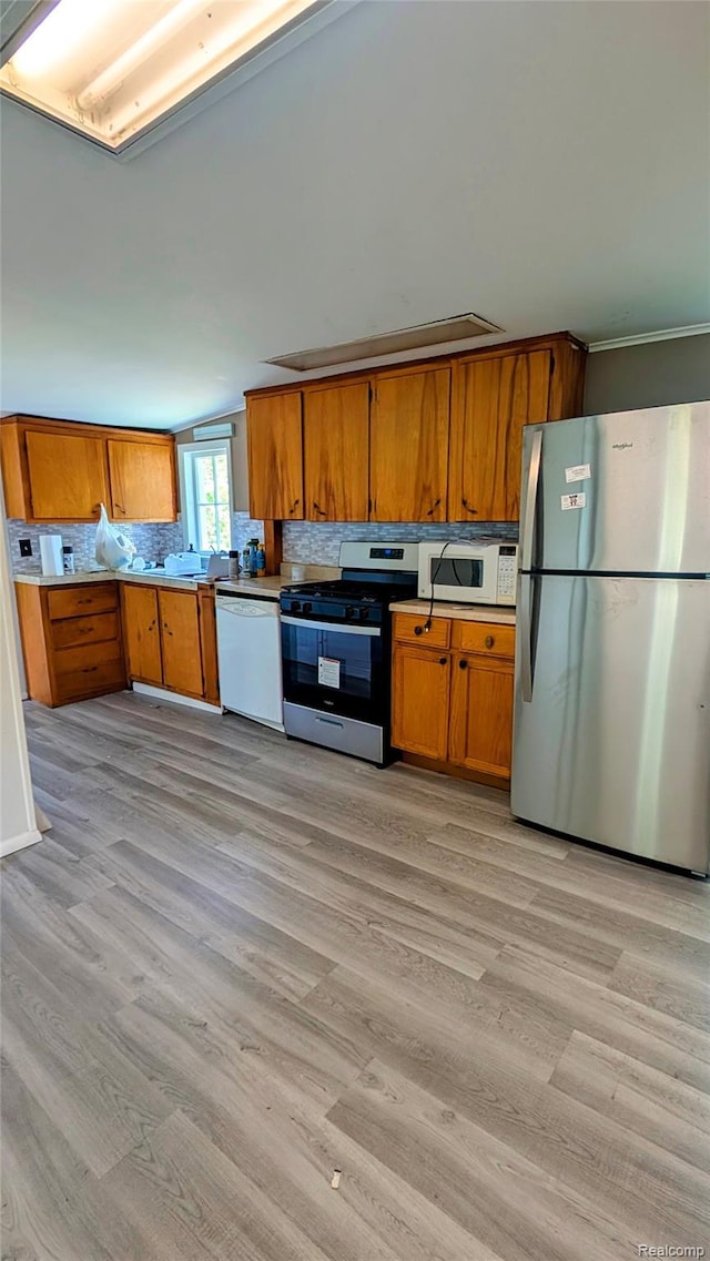 703 Queen St, Owosso, MI 48867 - kitchen with stainless steel appliances, brown cabinetry, light wood-type flooring, light countertops, and crown molding