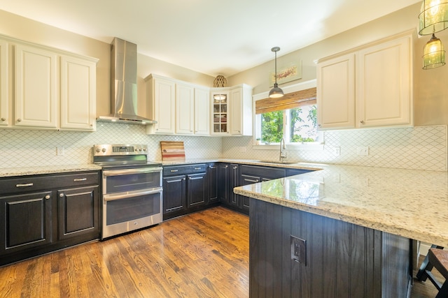 1050 Long Leaf Ct, Brighton, MI 48116 - kitchen featuring range with two ovens, wall chimney range hood, a sink, and light stone counters