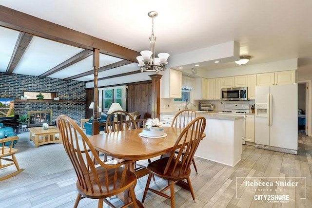 9409 Whitneyville Ave SE, Alto, MI 49302 - dining space featuring light wood-style floors, a chandelier, brick wall, beamed ceiling, and a fireplace