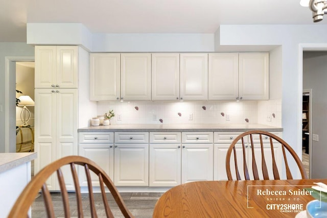 9409 Whitneyville Ave SE, Alto, MI 49302 - kitchen featuring light countertops, tasteful backsplash, wood finished floors, and white cabinetry