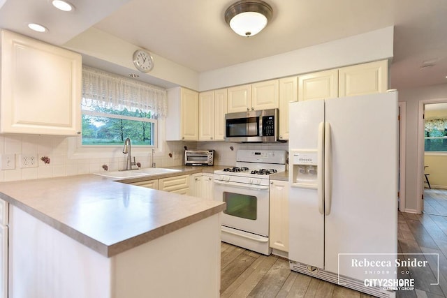 9409 Whitneyville Ave SE, Alto, MI 49302 - kitchen featuring white appliances, a sink, light wood-style flooring, a peninsula, and recessed lighting