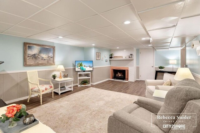 9409 Whitneyville Ave SE, Alto, MI 49302 - living area with wood finished floors, wainscoting, a brick fireplace, a paneled ceiling, and recessed lighting
