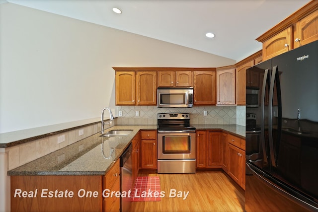 32 Tuscany Cir, Saginaw, MI 48603 - kitchen with stainless steel appliances, a sink, lofted ceiling, brown cabinetry, and recessed lighting