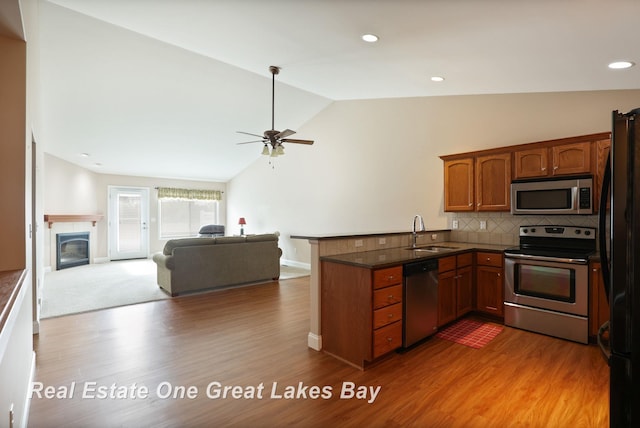 32 Tuscany Cir, Saginaw, MI 48603 - kitchen featuring appliances with stainless steel finishes, a peninsula, vaulted ceiling, ceiling fan, and wood finished floors