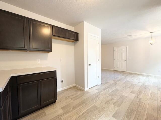 8121 Bowens Mill Rd, Middleville, MI 49333 - kitchen featuring light wood-style flooring, light countertops, dark brown cabinets, baseboards, and open floor plan