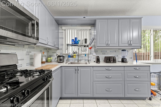 5908 Gilman St, Garden City, MI 48135 - kitchen featuring stainless steel appliances, gray cabinetry, a sink, tasteful backsplash, and a textured ceiling