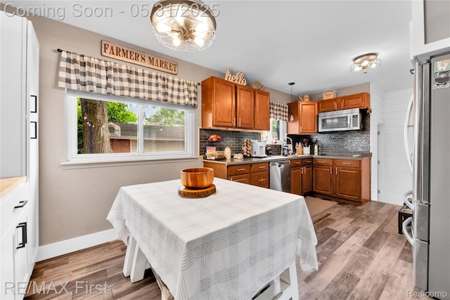 26242 Audrey Ave, Warren, MI 48091 - kitchen featuring appliances with stainless steel finishes, brown cabinetry, tasteful backsplash, and light wood-type flooring