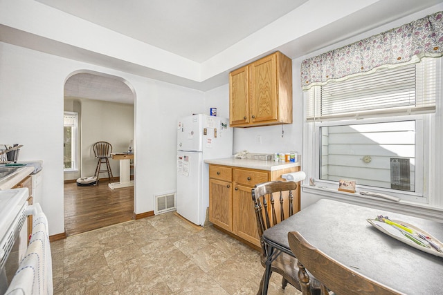 537 Wolverine Dr NE, Grand Rapids, MI 49505 - kitchen with freestanding refrigerator, arched walkways, light countertops, baseboards, and brown cabinets
