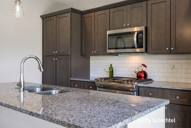 334 Terrace Point Cir Unit 33, Muskegon, MI 49440 - kitchen with appliances with stainless steel finishes, a sink, dark brown cabinetry, light stone counters, and backsplash