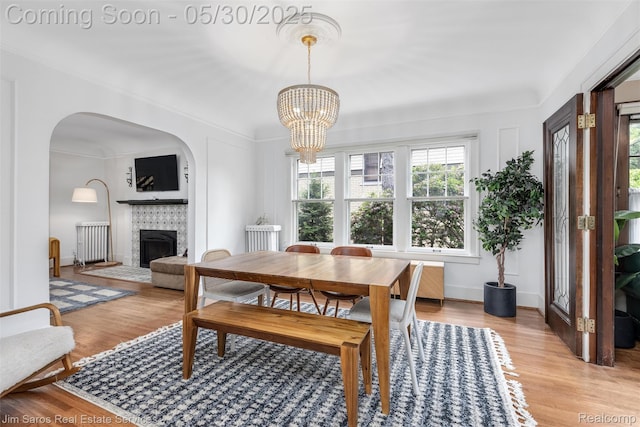 1377 Bishop Rd, Grosse Pointe Park, MI 48230 - dining room featuring radiator, a chandelier, a tiled fireplace, light wood finished floors, and ornamental molding