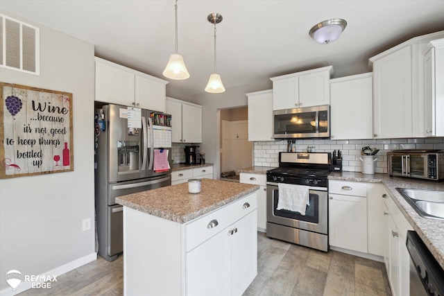 9416 Sunrise Ln, Davison, MI 48423 - kitchen featuring appliances with stainless steel finishes, a kitchen island, backsplash, white cabinets, and light wood-type flooring