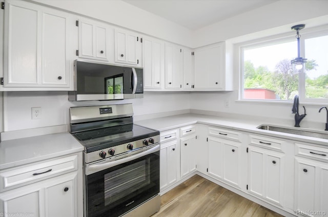 2680 N Lake George Rd, Metamora, MI 48455 - kitchen with stainless steel appliances, a sink, light countertops, white cabinetry, and light wood-style floors