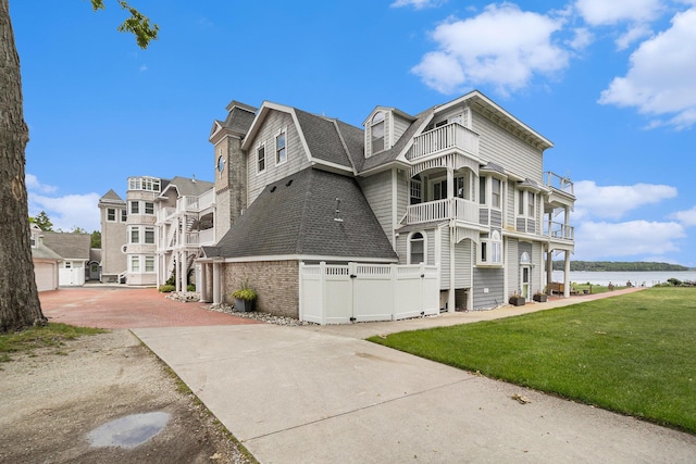 6180 Murray Rd Unit 301, Whitehall, MI 49461 - view of property exterior featuring a balcony, a shingled roof, a water view, and a gambrel roof