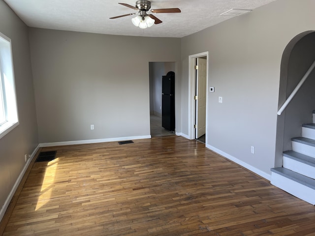 911 Muskegon Ave NW, Grand Rapids, MI 49504 - empty room featuring a ceiling fan, wood finished floors, stairway, arched walkways, and a textured ceiling