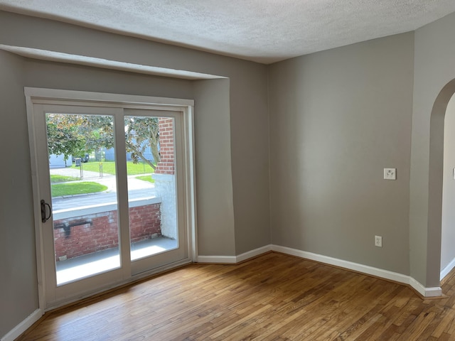 911 Muskegon Ave NW, Grand Rapids, MI 49504 - spare room with light wood-style flooring, arched walkways, baseboards, and a textured ceiling