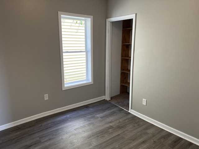 911 Muskegon Ave NW, Grand Rapids, MI 49504 - unfurnished bedroom with dark wood finished floors, a closet, and baseboards