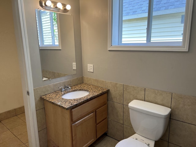 911 Muskegon Ave NW, Grand Rapids, MI 49504 - bathroom featuring plenty of natural light, toilet, vanity, a wainscoted wall, and tile walls