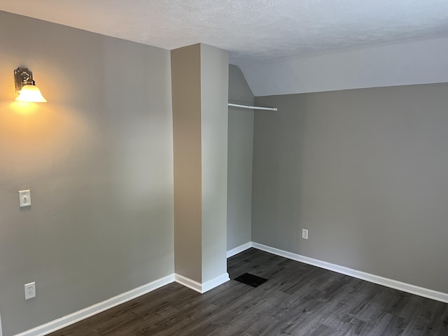 911 Muskegon Ave NW, Grand Rapids, MI 49504 - spare room with dark wood finished floors, baseboards, lofted ceiling, and a textured ceiling