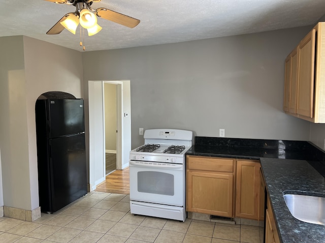 911 Muskegon Ave NW, Grand Rapids, MI 49504 - kitchen featuring freestanding refrigerator, white gas stove, light tile patterned floors, and ceiling fan
