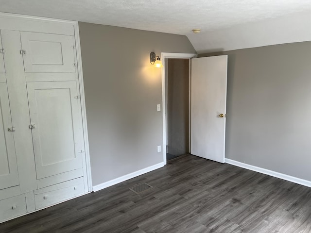 911 Muskegon Ave NW, Grand Rapids, MI 49504 - unfurnished bedroom featuring baseboards, dark wood finished floors, and vaulted ceiling