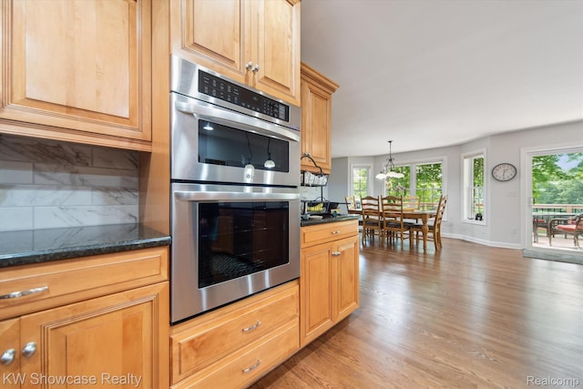 9120 Pineview Lake Dr, Linden, MI 48451 - kitchen featuring stainless steel double oven, light wood finished floors, baseboards, dark stone counters, and hanging light fixtures