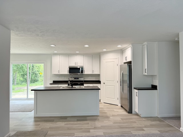 2827 Green Acres Dr, Mulliken, MI 48861 - kitchen featuring appliances with stainless steel finishes, a sink, dark countertops, white cabinetry, and light wood finished floors