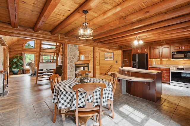 1750 Fox Rd, Jackson, MI 49201 - dining space with wooden ceiling with exposed beams, a chandelier, light tile patterned flooring, log walls, and a stone fireplace