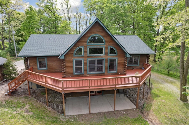 1750 Fox Rd, Jackson, MI 49201 - rear view of house featuring log siding, a wooden deck, a patio, a lawn, and a shingled roof