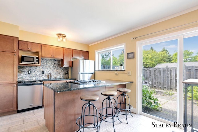 2420 Abbington Dr SE Unit 40, Grand Rapids, MI 49506 - kitchen featuring stainless steel appliances, a sink, backsplash, a breakfast bar area, and brown cabinets