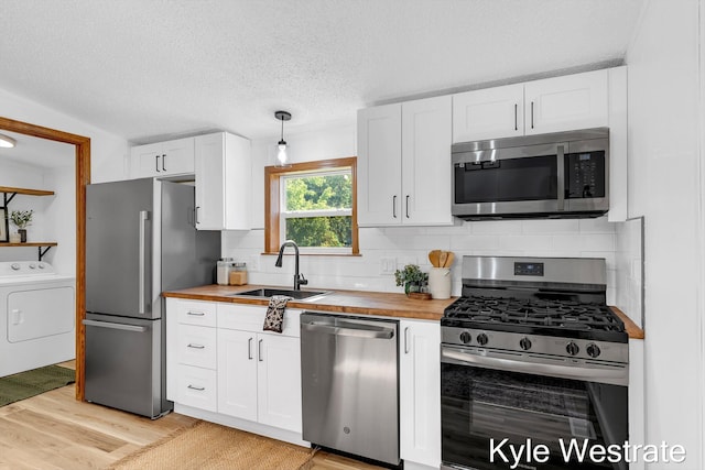 206 Pearl St, Sheridan, MI 48884 - kitchen with appliances with stainless steel finishes, washer / clothes dryer, a sink, wooden counters, and white cabinetry
