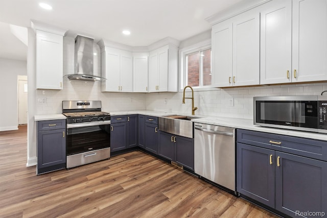 2547 Seyburn St, Detroit, MI 48214 - kitchen featuring stainless steel appliances, wall chimney exhaust hood, a sink, white cabinets, and wood finished floors
