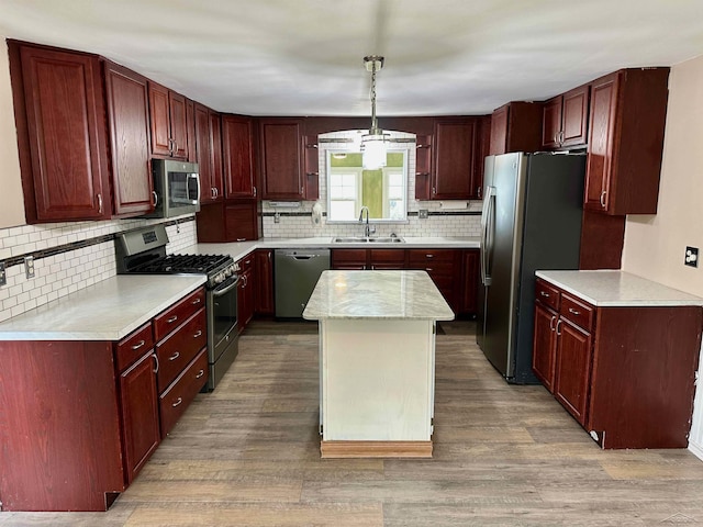 13405 S Gera Rd, Birch Run, MI 48415 - kitchen with stainless steel appliances, reddish brown cabinets, light wood-style floors, backsplash, and a kitchen island