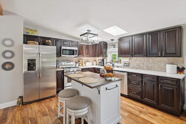 5885 Lammers Rd, Hastings, MI 49058 - kitchen with appliances with stainless steel finishes, a skylight, tasteful backsplash, a kitchen bar, and light wood-style flooring