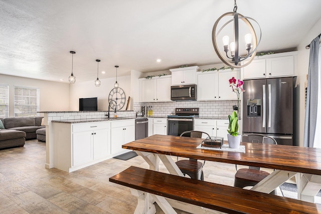 10900 Vine Leaf Cir, Allendale, MI 49401 - kitchen featuring stainless steel appliances, a peninsula, a sink, a chandelier, and light wood-type flooring