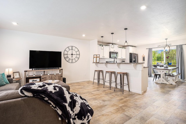 10900 Vine Leaf Cir, Allendale, MI 49401 - living area with light wood-style floors, recessed lighting, baseboards, and a chandelier