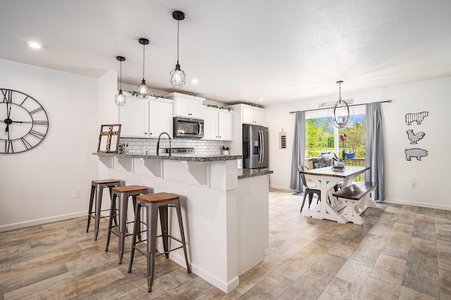 10900 Vine Leaf Cir, Allendale, MI 49401 - kitchen featuring appliances with stainless steel finishes, a chandelier, a breakfast bar area, tasteful backsplash, and white cabinetry
