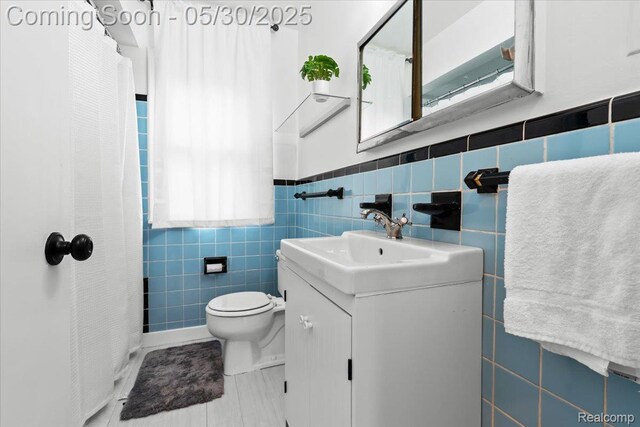 114 N Connecticut Ave, Royal Oak, MI 48067 - full bathroom with tile walls, vanity, toilet, a shower with curtain, and a wainscoted wall